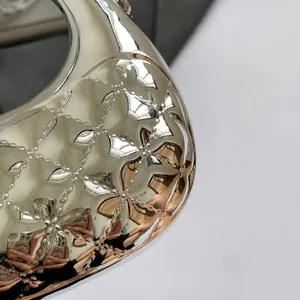 Macro shot of silver quilted faux leather with metallic flower detail and glossy finish