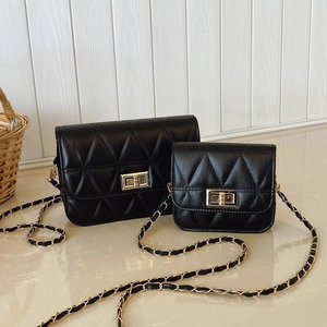 Sac bandoulière en cuir matelassé noir avec chaîne dorée sur une surface en marbre