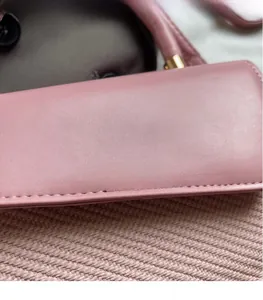 Détail du sac à main en cuir rose avec coutures fines et texte Fashion & Bags imprimé