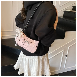 Detail of pink bow bag with black heart prints, lace and pearl charm on a shoulder strap