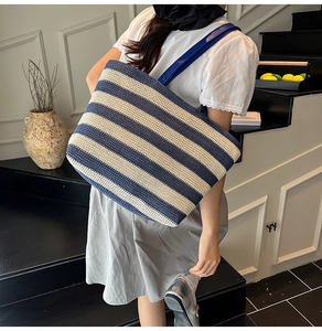 Dettaglio della borsa tote intrecciata a righe bianche e blu indossata da modella