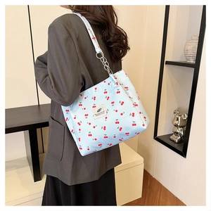 Detail view of light blue cherry print tote bag with metal chain strap and cloth patch