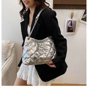 Detail of silver quilted bucket bag with star ornament and chain strap on a model