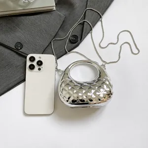 Silver metallic mini bag with diamond texture next to a phone for size comparison