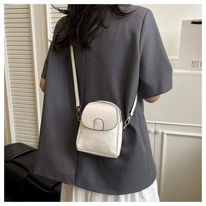 Rear view of a model wearing a cream mini crossbody phone bag with a slim strap