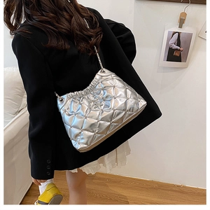Chic silver quilted bucket bag with chain strap shown on a model in a trendy outfit