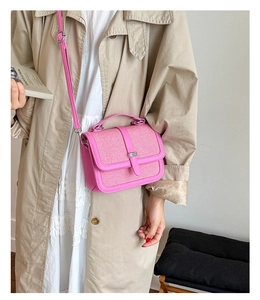 Pink woven leather crossbody bag styled with a beige coat and pleated skirt outfit