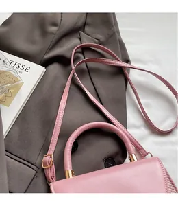 Détail du sac à main en cuir PU rose avec coutures tressées et lettrage doré chic