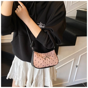 Detail of pink ruffled shoulder bag with black heart patterns and metal bow detail