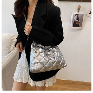 Detailed view of silver metallic quilted bucket bag with chain strap and stud accents