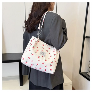 Detail view of cherry print canvas tote bag featuring metal ring chain strap on model