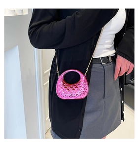 Detail of metallic rose pink shell handbag with quilted diamond pattern and gold chain