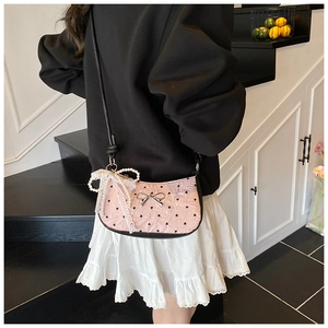 Close-up of pink heart-print shoulder bag featuring silver bow and pearl lace pendant