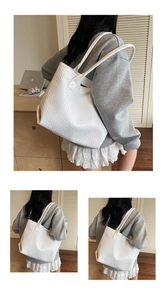 Detail of white woven texture tote bag showing intricate intrecciato pattern and dual straps