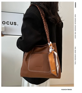 Detail of brown lychee leather tote bag with braided strap and patterned silk scarf