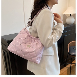Pink quilted leather bucket bag with silver studs and star emblem worn by a model
