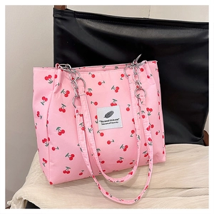 Detail of pink cherry print tote bag with silver metal chain handle and logo patch