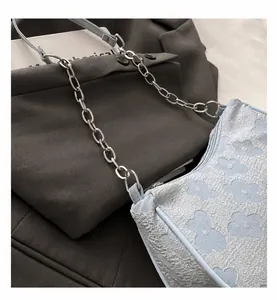 Detailed view of light blue floral jacquard baguette bag featuring silver chain strap