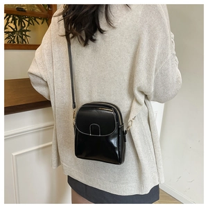 Close-up of a glossy black crossbody phone bag with gold hardware and contrast stitching