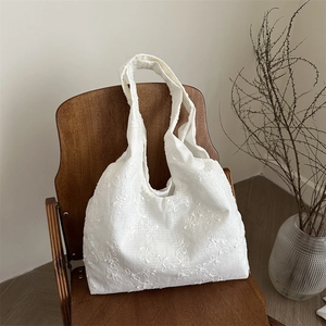 White floral embroidery canvas tote bag on a vintage wooden chair with a clean background