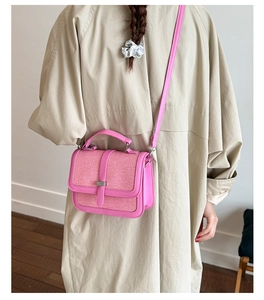 Detailed back view of a pink woven crossbody bag styled with a minimalist beige coat