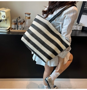 Detail of a large black and white striped woven tote bag with premium leather straps