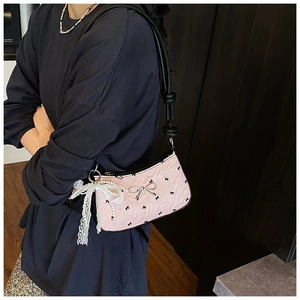 Close-up of pink baguette bag with lace bow charm and silver metallic bow hardware