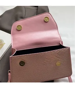 Détail du rabat tissé rose et des fermoirs magnétiques dorés sur le sac à bandoulière
