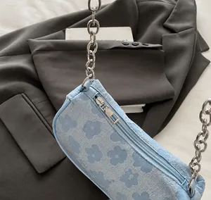 Close-up of a light blue floral baguette bag showing smooth zipper and chain strap.