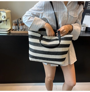 Dettaglio di una borsa tote intrecciata a righe con manici in pelle sul bancone