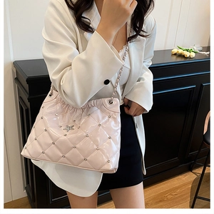 Close-up of pink quilted bucket bag with star logo and chain strap on female model