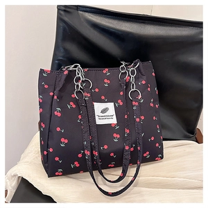 Close-up of black cherry print tote bag featuring silver chain and woven handles