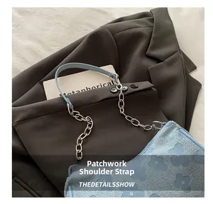 Close-up of a blue floral textured baguette bag with a silver chain and leather strap.