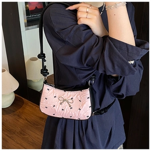 Close-up of pink silk shoulder bag with black bows and silver metal buckle