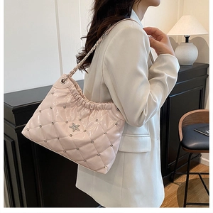 Detail of quilted beige bucket bag with star ornament and sparkling crystal accents