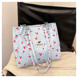 Detail of light blue cherry print tote bag featuring a silver metal chain canvas strap