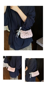 Detail of pink quilted baguette bag with black bows, lace charms, and pearl accents