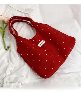 Détail du sac fourre-tout en toile rouge à motif floral et étiquette Creative Cat