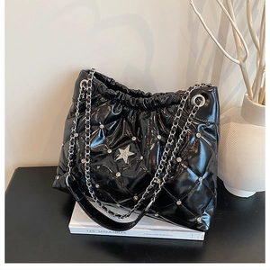 Detail of glossy black quilted tote bag with silver star diamonds and chain strap