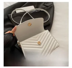 Macro shot of white quilted chevron faux leather bag with polished gold magnetic closure