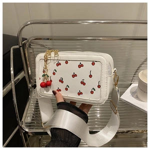 Detailed view of white cherry print square crossbody bag featuring wide webbed strap