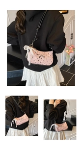Detail of pink crescent bag with black heart patterns and decorative lace bow charm