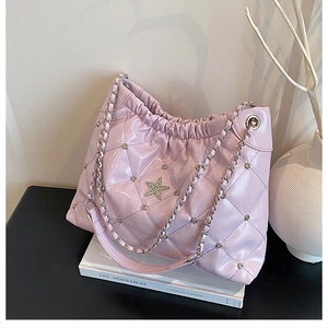Detail of pink quilted bucket bag with star rhinestone on black table next to books