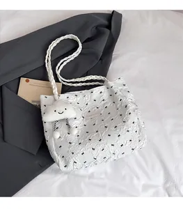 Detail of white embossed tote bag featuring black bow print and cloud plush pendant accessory