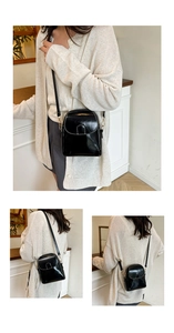 Detail of a black crossbody phone bag with contrast white stitching and gold hardware