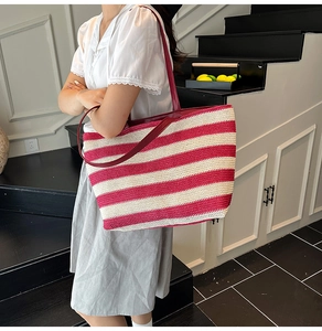 Dettaglio di una borsa tote grande in paglia a righe rosse e bianche con manici lunghi
