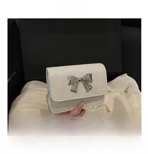 Detail of white animal texture bag with silver metal bow and elegant chain strap