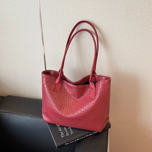 Red woven leather tote bag with long double straps on a sofa for minimalist office style