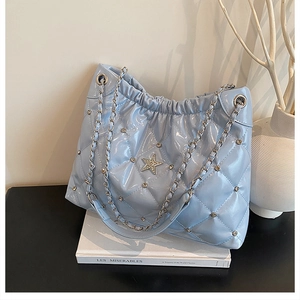 Detail of light blue quilted bucket bag with rhinestone star and silver chain strap