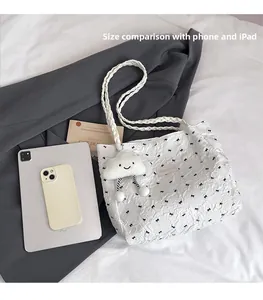 White tote bag with bow patterns and plush charm shown next to iPad for size scale